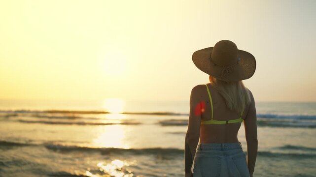 Woman stand quietly by sea at sunrise, enjoy peaceful moment of mindfulness and reconnecting with nature. Wellness, mental wellbeing and slow living concept