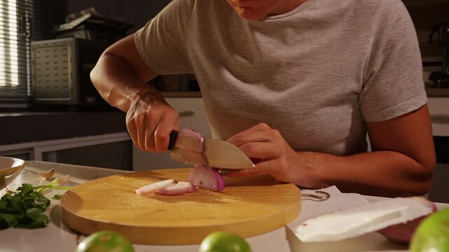 Woman Slices Red Onion on Wooden Board in Sunlit Kitchen, Fresh Avocados Limes and Herbs Support Healthy Food Preparation