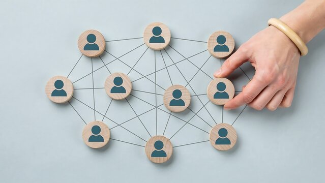 Networking concept with wooden figures connected by lines and a hand adding one more figure. This represents a strong social connection and the expansion of a network