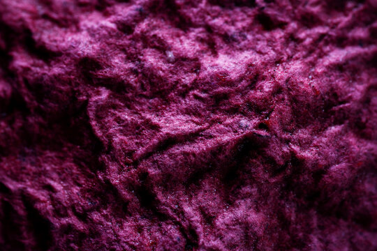 Extreme close up of purple handmade paper clay with a structure and rough texture. Paper recycling. Selective soft focus, shallow depth of field.