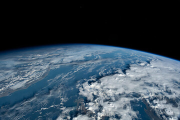 Fototapeta premium Earth from orbit showing atmosphere and vast cloud formations over ocean.