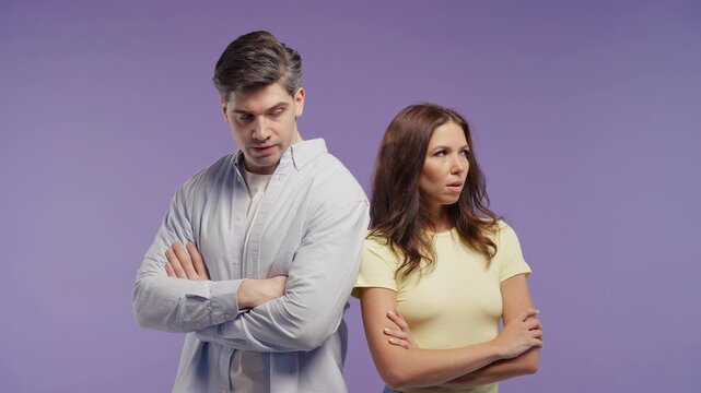 Upset young couple standing back to back with folded arms after an argument. Relationship conflict, misunderstanding, emotional distance, tension, communication problems and unresolved disagreement.
