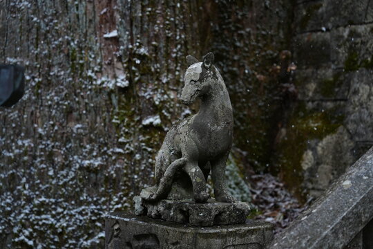 Close up of traditional Japanese stone wolf statue in winter snow scene