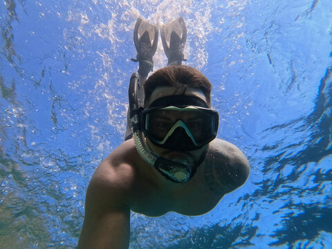 Underwater bottom view of man snorkeling with mask and fins in clear blue Mediterranean waters of Saint-Jean-Cap-Ferrat France