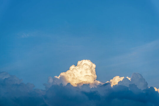 Blue sky with sunlit cumulus clouds towering