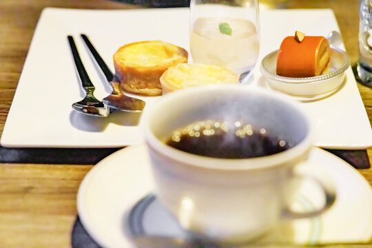 温かいホットコーヒーと奥に見えるスイーツプレート