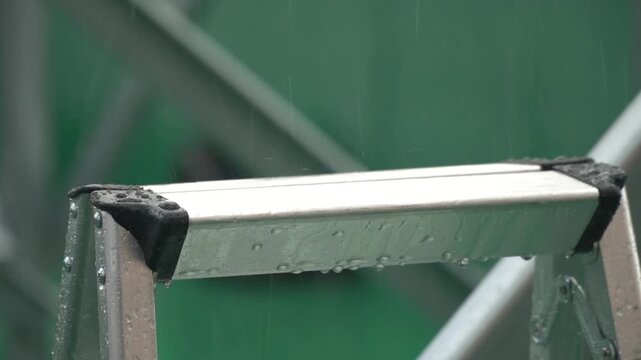 Close up of Raindrops Falling on a Silver Metallic Ladder During a Shower