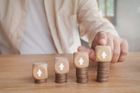 Financial growth concept with stacked coins and wooden blocks showing upward arrows, investment performance, business growth, wealth building, increasing revenue, asset growth and financial success