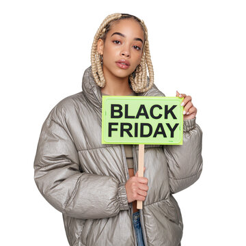 Confident young woman with blonde braided hair in a silver puffer jacket holding a green Black Friday sign against isolated on transparent or white background, png