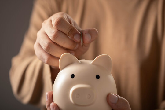 Personal savings and financial planning featuring a hand depositing a coin into a piggy bank, money management, wealth accumulation, saving habits, financial goals, and long-term investment growth.