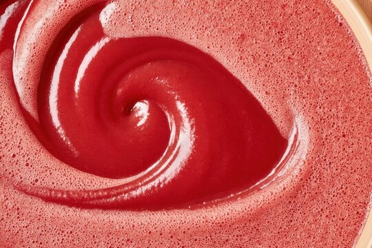 Deep red grape must swirling in fermentation tank with frothy bubbles and glossy texture