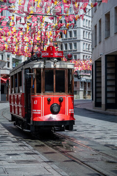 Istanbul, turkey, august 2, 2025 iconic red tram moving along istiklal avenue, beyoglu, with pedestrians and colorful flags decorating the city street on a sunny day