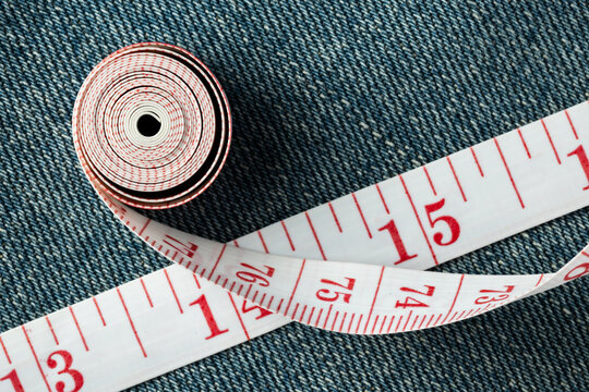 Tape measure curving on denim jeans fabric background