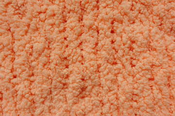 Orange fluffy fabric forms soft textured surface © Iryna Miadzvedzeva