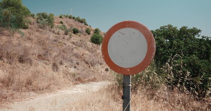 Blank prohibition traffic sign on dry dirt road in arid countryside, warning of restricted access and wildfire risk, conveying a message of caution and safety in remote natural landscapes.