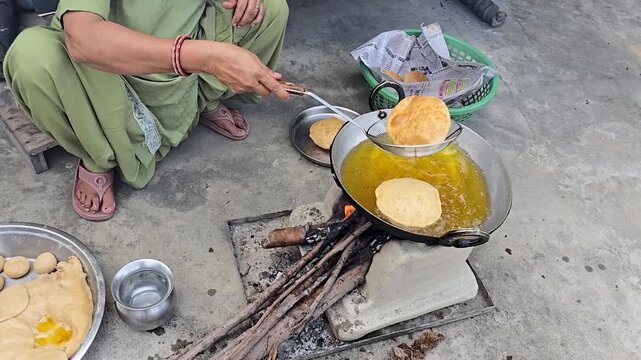 Traditional indian street food cooking poori in a metal pan over a wood fire a woman skillfully