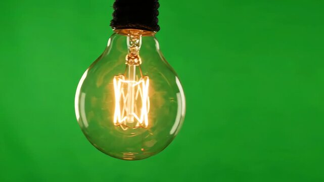 A realistic incandescent light bulb swinging back and forth against a bright green screen background with a glowing filament and subtle glass reflections