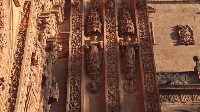 Plateresque facade of the Convent of San Esteban in Salamanca, Spain showing its rich sculptural detail and religious statues under a warm sunset light