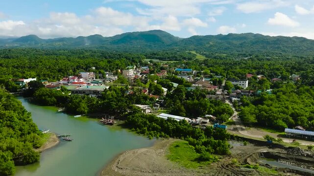 Tropical Island with houses and river. Looc, Poblacion. Blue sky and clouds. Tablas Island. Romblon, Philippines.