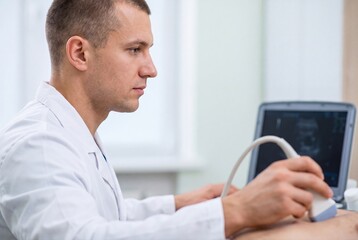 Fototapeta premium Male doctor performing ultrasound examination in modern medical clinic