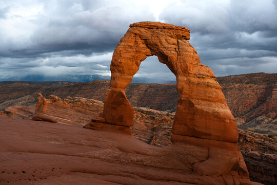 Dark clouds rolling behind the iconic Delicate Arch at Arches National Park