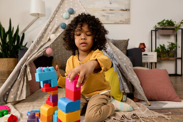 Happy african american boy building with colorful blocks in a modern home © LIGHTFIELD STUDIOS