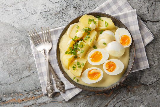 Senfeier hard boiled eggs in creamy mustard sauce with potato close-up in a plate on the table. Horizontal top view from above