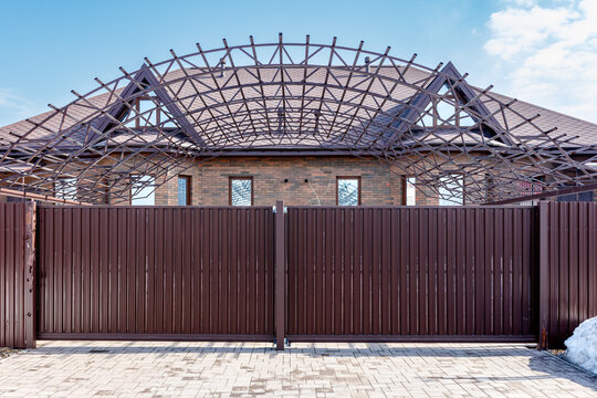 Metal fence stands before a house under construction
