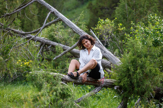 Woman sits on fallen log in forest