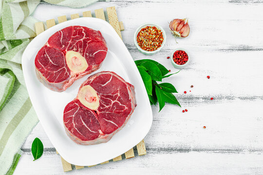 Raw ossobuco beef meat with spices and fresh herbs. Veal shank steak, traditional Italian ingredient