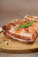 Obraz premium Raw marinated pork ribs with rosemary, spices and garlic on a wooden cutting board with a meat fork