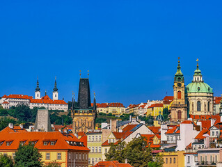 Obraz premium Panoramic cityscape of Prague featuring castle, historic architecture, red roof buildings, and the vibrant atmosphere of the historic European capital