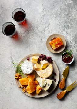 Cheese platter assortment with red wine glasses and honeycombs. Grey background. Copy space. Top view.