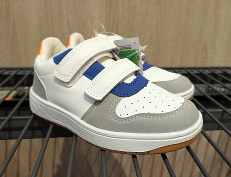 Vista de cerca de un par de zapatillas deportivas infantiles con tiras de velcro, en expositor de una tienda de deportes