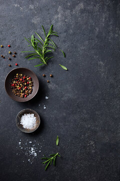 Food background with seasoning ingredients and fresh organic rosemary on black slate board. Dark background. Copy space. Top view.
