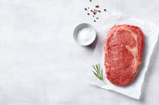 Fresh uncooked beef steak border mockup on bright concrete surface for restaurant menu template. Grey background. Close up, copy space, top view.