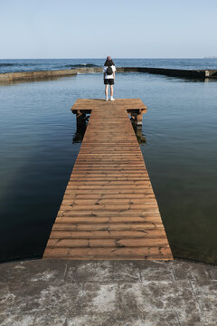 Young Girl Standing on Wooden Pier Looking at the Atlantic Ocean in Tenerife