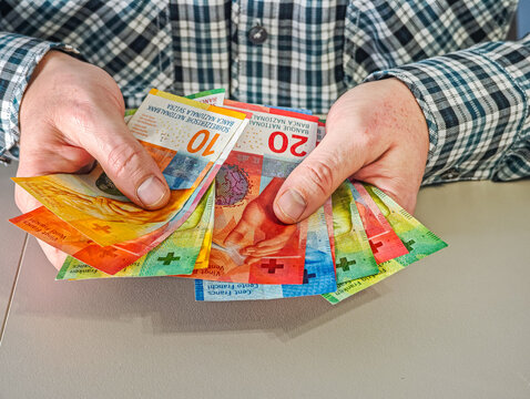 Close up of male hands holding fan of Swiss Franc banknotes CHF currency for savings and investment