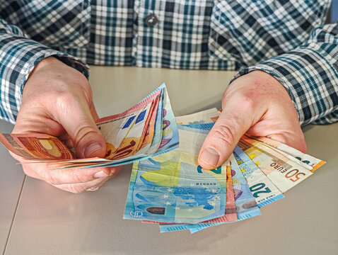 Hands of businessman holding stack of 50 and 10 Euro banknotes, EUR currency cash for payment