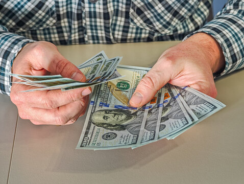 Close up of male hands holding fan of 100 dollar bills, wealth and financial stability concept