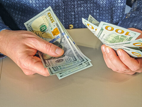 Businessman counting one hundred US dollar banknotes, hands holding stack of USD cash money