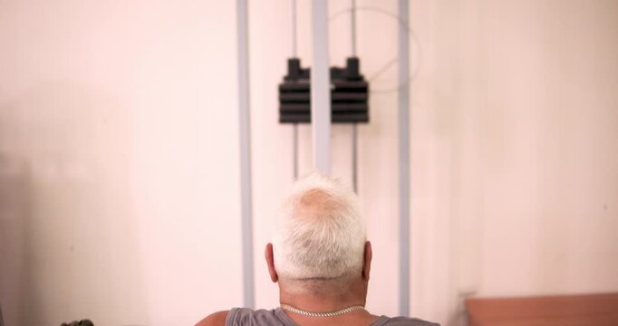 In a modern gym, a man performing lat pulldown with concentration, demonstrating strength training and fitness.