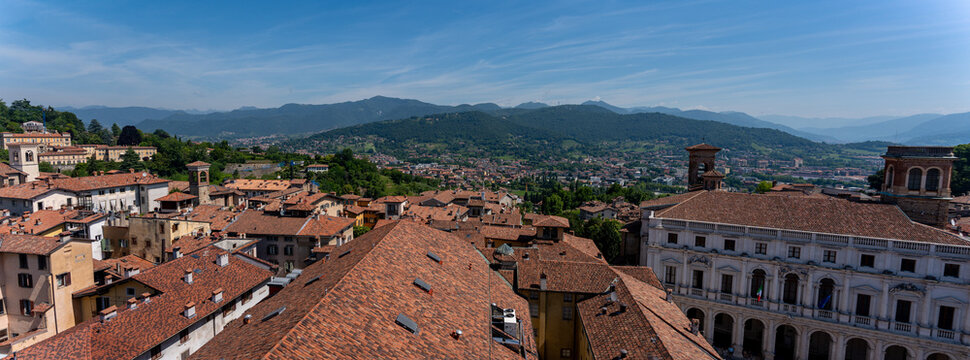 Panoramic view of Bergamo upper town rooftop architecture and mountains in Lombardy Italy sunny summer landscape blue sky
