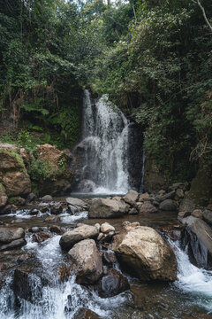 Beautiful Cipamingkis Waterfall surrounded by lush tropical forest in Bogor, West Java, Indonesia, ideal for travel, nature, and ecotourism concepts