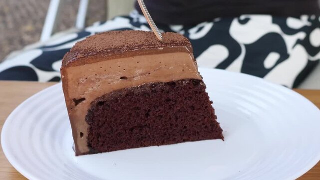 Taking a bite of creamy chocolate mousse cake with a fork, macro shot