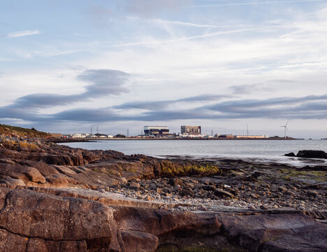 Coastal rocks by calm sea with distant Nuclear Power Station on 
