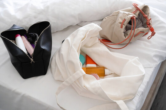 Cosmetic Bags with Personal Care Products on Bed
