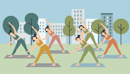 Fototapeta premium Diverse group of active women practicing triangle yoga pose on mats in a green city park with skyscrapers in the background.