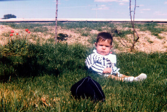 Little baby exploring green grass on spring day