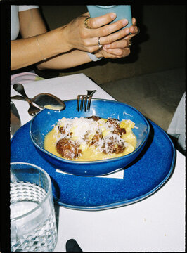Person holding phone taking picture of dinner bowl